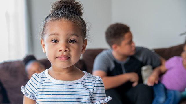 A young girl in the living room with her family.