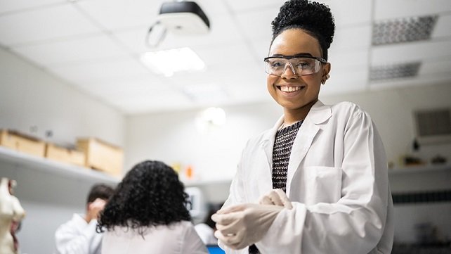 Excited student in a lab coat studying in a research lab