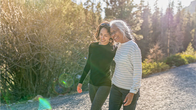 Two older woman walking together along the beach
