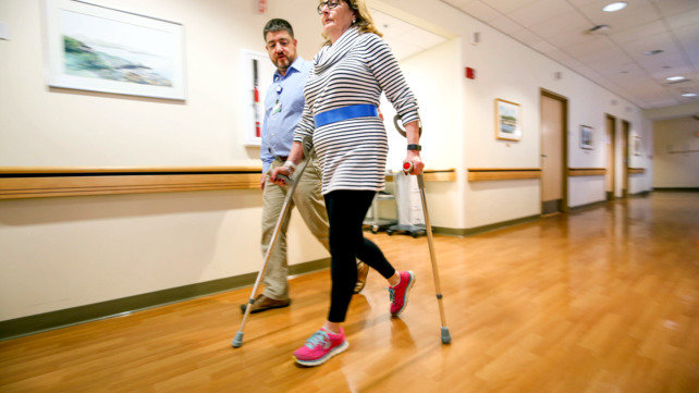A patient walks with a therapist.