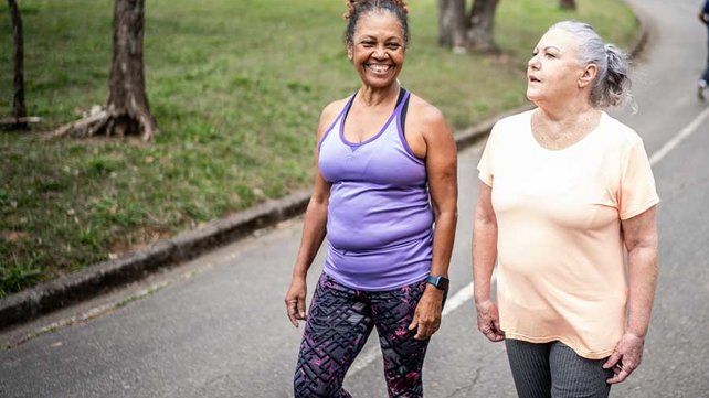 Two senior women walking in park