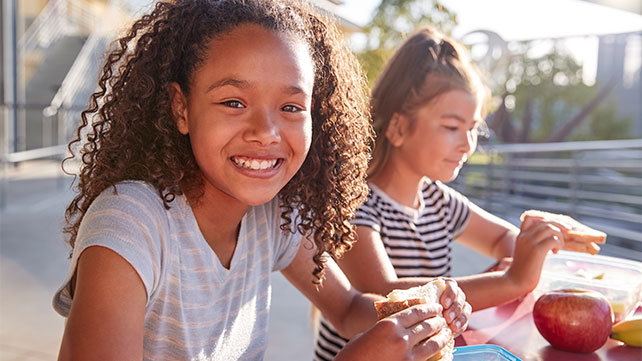 Two children eating their lunch outside.