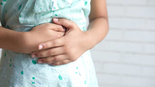Adolescent holding stomach due to stomach ache