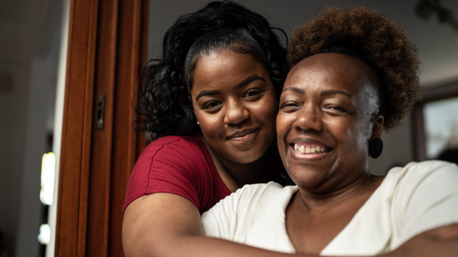 A mother and daughter smiling and hugging