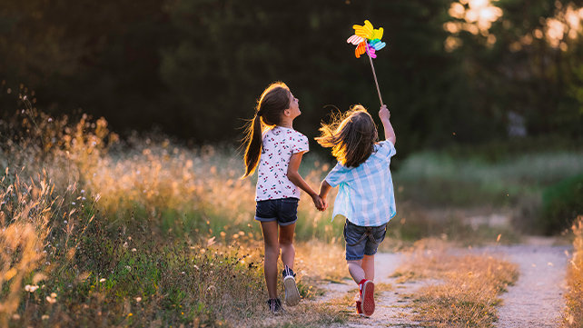 Two children playing with a pinwheel outside
