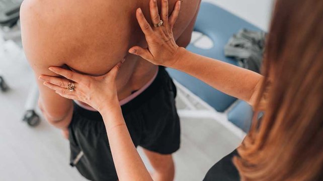 Young adult with physical therapist for scoliosis