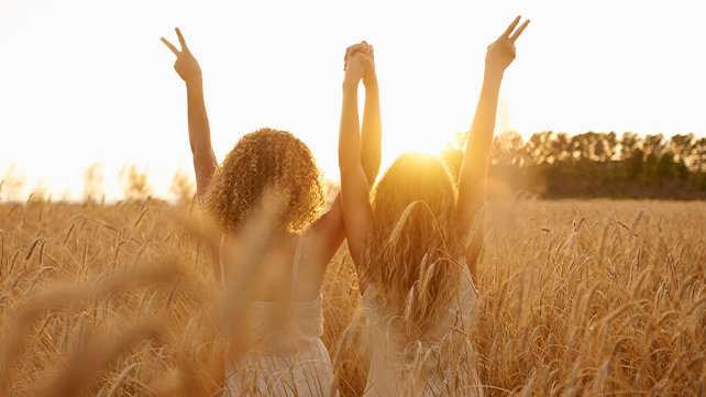 Two children with their arms joyously in the air facing toward the setting sun