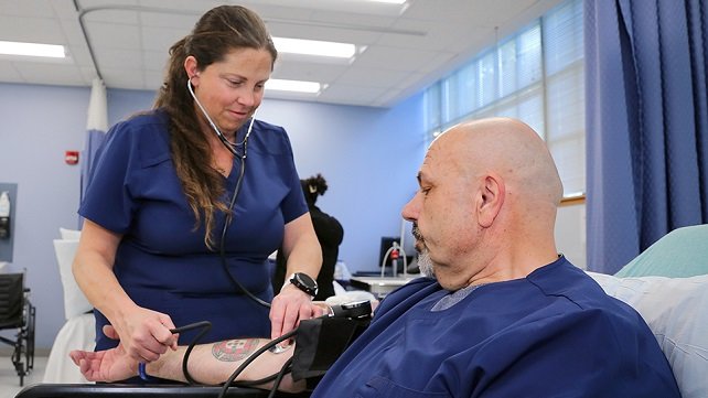 A student in the nursing assistant training program with a patient.