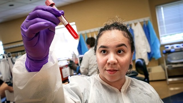 Lab technician looking at solution in a test tube.