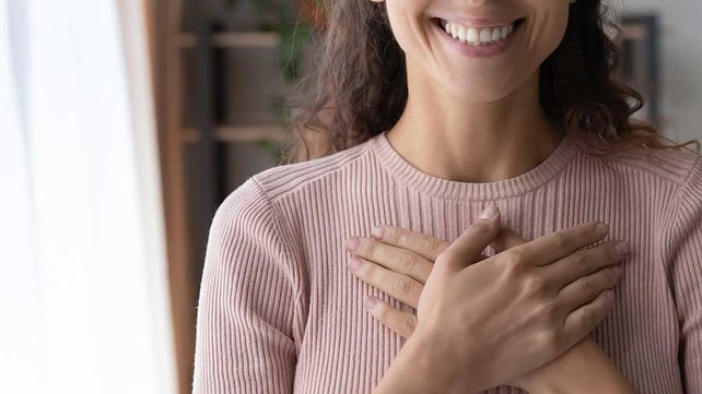 Women meditating with hands over heart