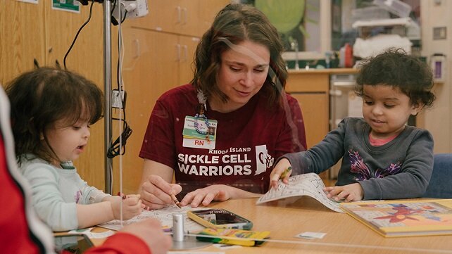An employee at Hasbro Children's working with two young children