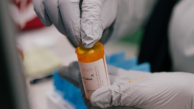 Gloved hands holding a prescription bottle