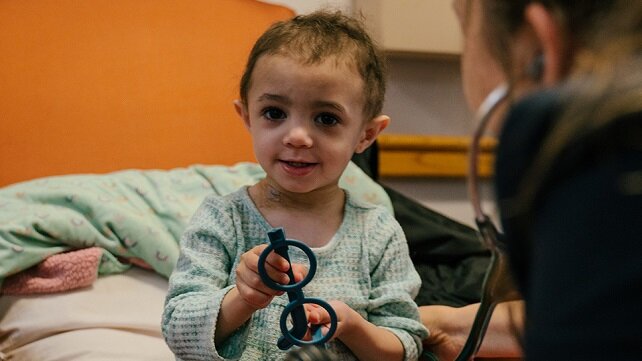 Very young patient holding a pair of glasses and getting a medical check-up