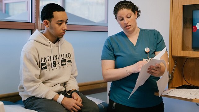 Young adult speaking with a health employee in a medical examination room