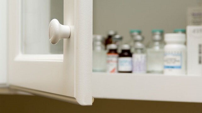 Photo of an open medicine cabinet full of prescription bottles