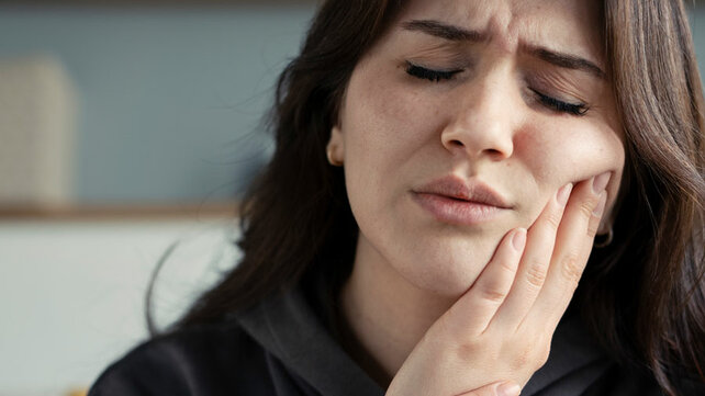 Women holding jaw in pain