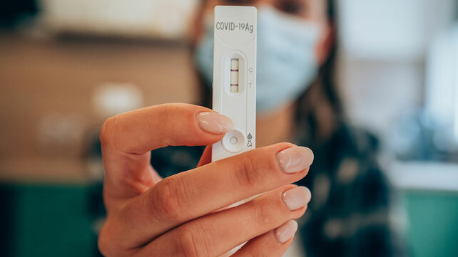 Photo of a woman holding up a COVID test