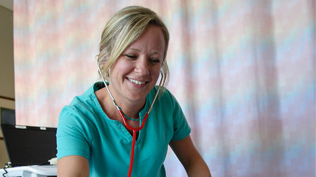 Female Morton Hospital employee wearing blue scrubs and a stethoscope