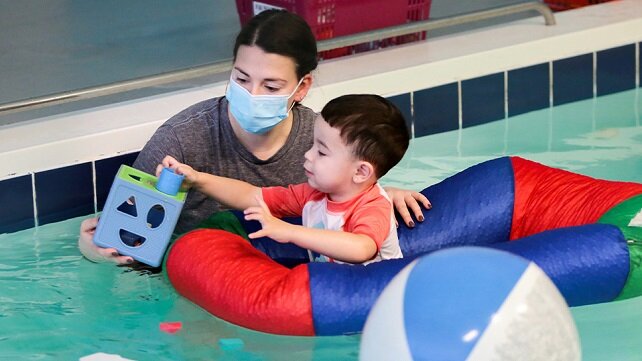 A pediatric therapist in the pool with a child patient at Hasbro Children's.