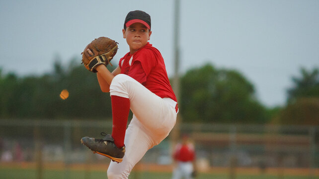 A boy on the pitcher's mound getting ready to throw a softball