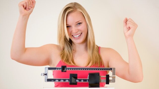 Smiling woman cheering herself on while on a scale