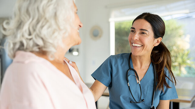 A woman clinician smiles at a patient.
