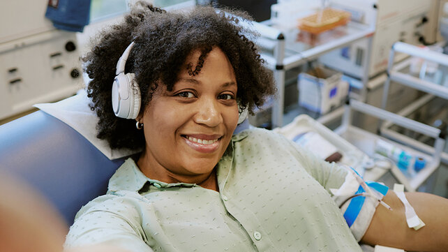 Smiling woman, wearing headphones, getting an infusion.