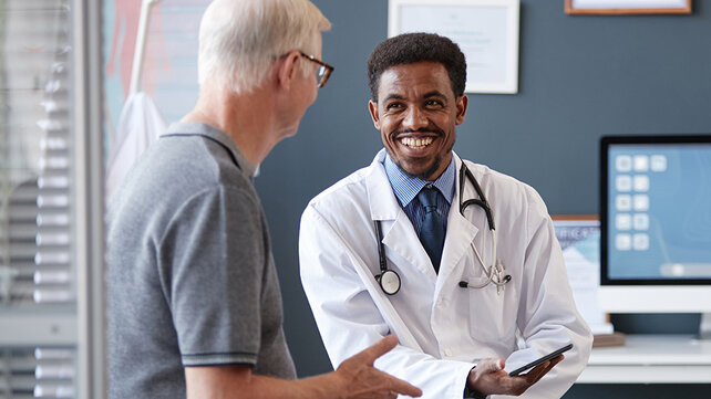 A doctor and patient talk. They are both smiling.