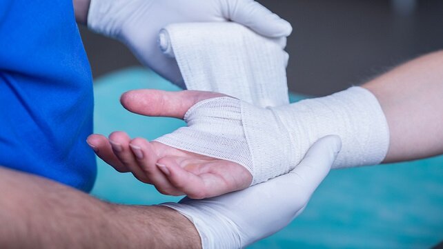 A wounded hand being bandaged.