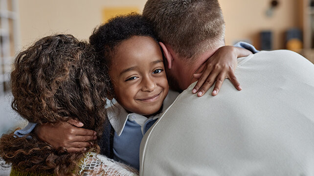 young boy hugging his mom and dad at the same time
