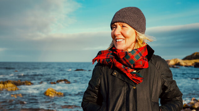 Women smiling at ocean on a cold day