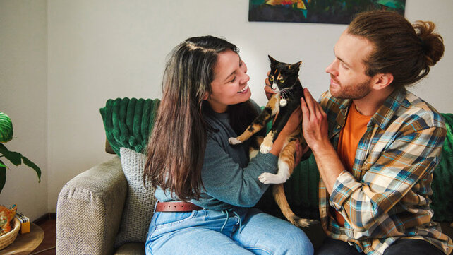 Young women and man sitting on couch with cat