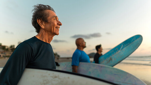 Three men holding surfboards on a beach.