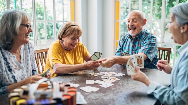 A happy group of older adults playing cards at a table.