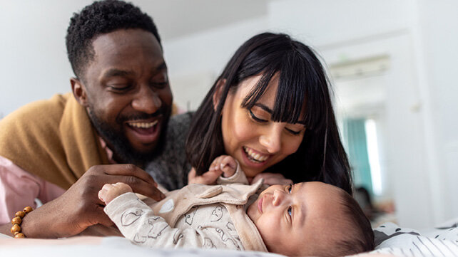 Mother and father smiling at their infant.