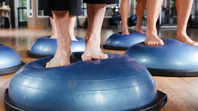 Image of people's feet on exercise balls in a gym