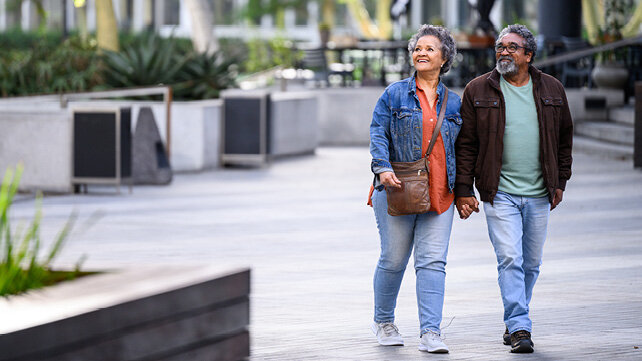An older couple walking and holding hands. 