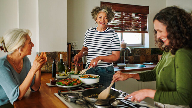 Three women gathered in a kitchen preparing food