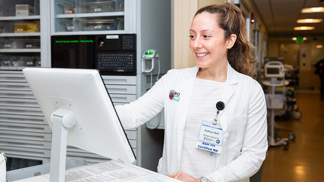 A clinician looks at work in front of a computer screen.