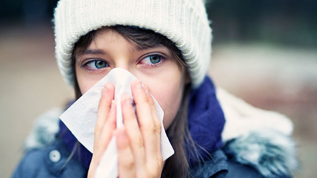 Woman with facial tissue blowing nose