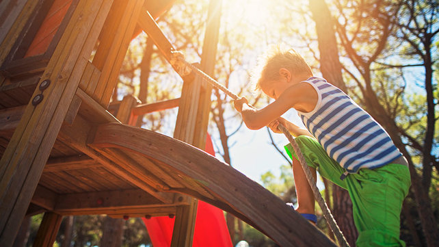 Young child climbing up a rope on playground equipment