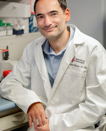 Portrait of Nikos Tapinos, MD, PhD, in a lab environment