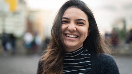 Woman smiling at camera with city sidewalk in the background