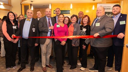 group of people standing togehter cutting a ribbon